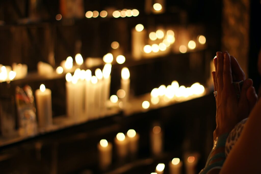 close up photograph of person praying in front lined candles