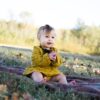 baby wearing yellow crochet long sleeve dress sitting on brown textile